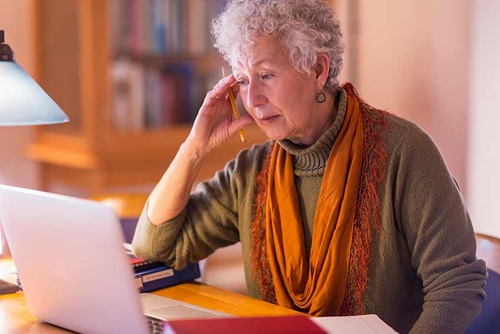 Patiente atteinte t d'ostéoporose - Jeanne à l'aide d'un ordinateur portable dans la bibliothèque